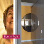 Zonnig interieur van studiopauke met een gele muur, hoogglans kasten en een vrolijke ronde spiegel.