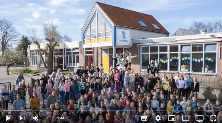 Een grote groep kinderen staat voor het schoolgebouw. Het is een van de openingsshots van de film van de leerlingen van De Fontein